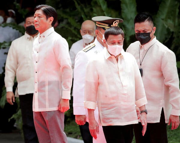 Politicians and other officials wear white shirts as they stand outdoors. Some are wearing face masks. 