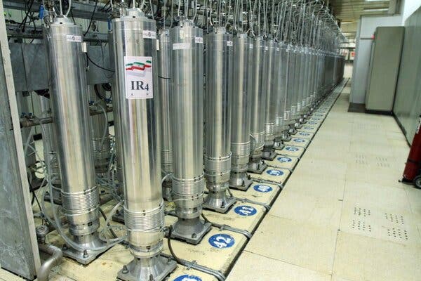 A room with rows of gleaming centrifuge machines, one of which bears a label that says “IR4” and has the Iranian flag on it.