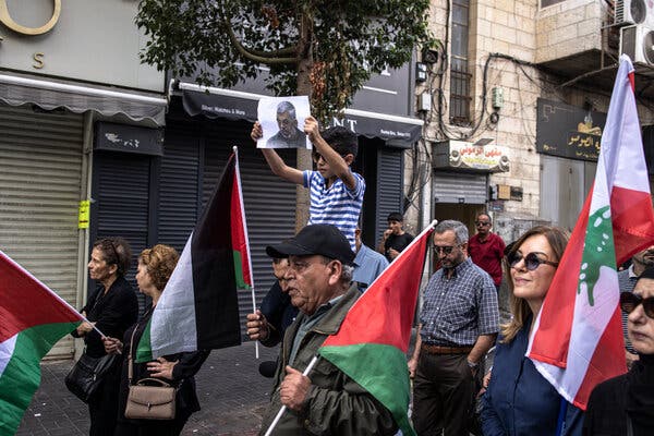 Demonstrators march, several holding Palestinian flags.