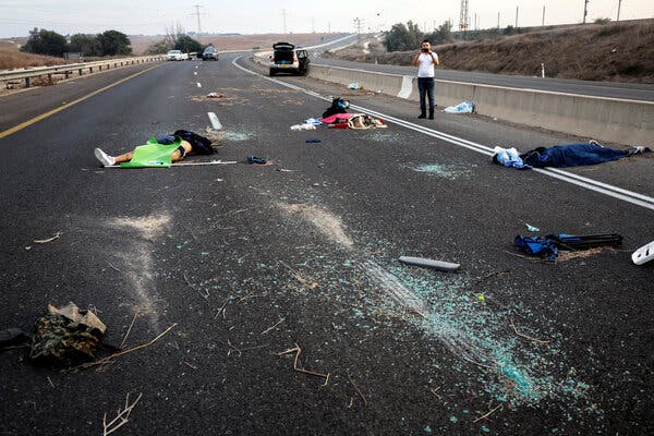 The bodies of four dead people lie on an empty highway, while a man takes a photo. 