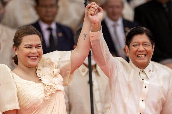 A woman and a man raising their hands together in victory. 