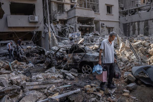 A man stands amid destroyed buildings and rubble.