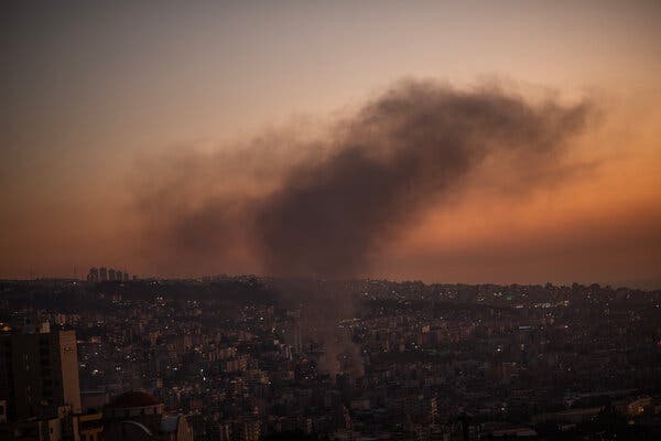 A plume of black smoke rises into an orange sky.