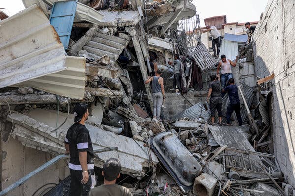 Several people climb over piles of debris from a collapsed building, trying to rescue a man caught in the rubble in northern Gaza. 