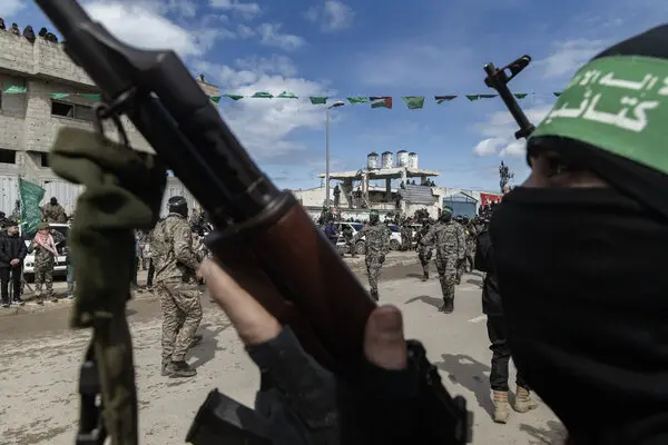 Armed Hamas militants wearing camouflage uniforms and masks walk on a street in February in the Gaza Strip. They are holding weapons.