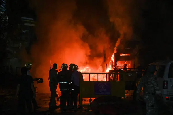 A burning car and a silhouette of a firefighter in front of it.