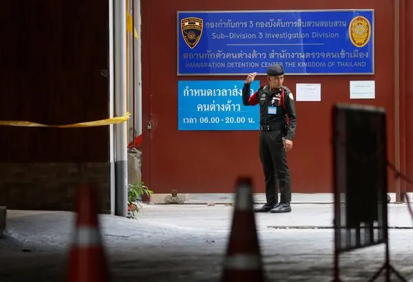 A man in uniform stands outside a building with a sign that reads 