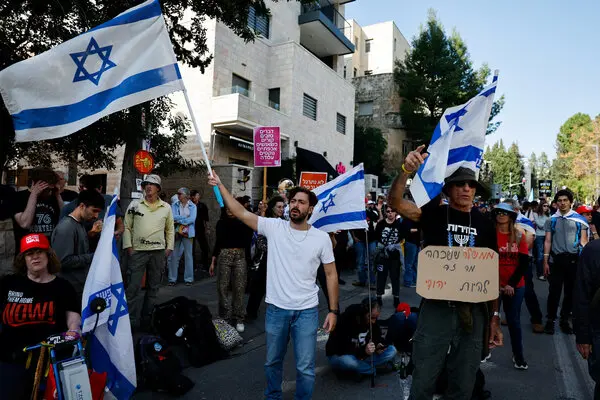 Protesters carry Israeli flags in a residential area.