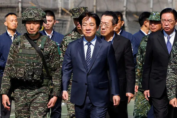 Several men, some in suits, others in camouflage military uniforms, walk in a group.