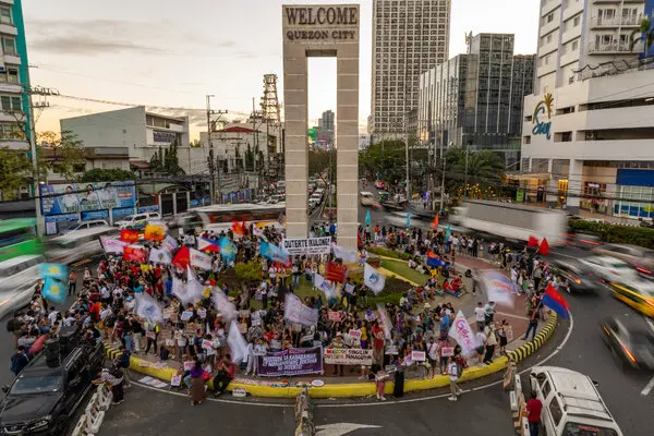 A large group of people gathered at a major roundabout, waving flags and holding banners.