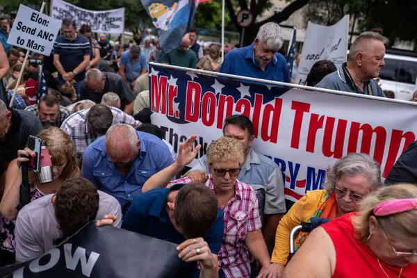 A crowd of people stands near a large banner that reads 