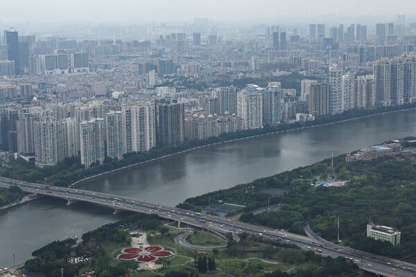 The skyline of Guangzhou, China, a long row of towers next to a river.