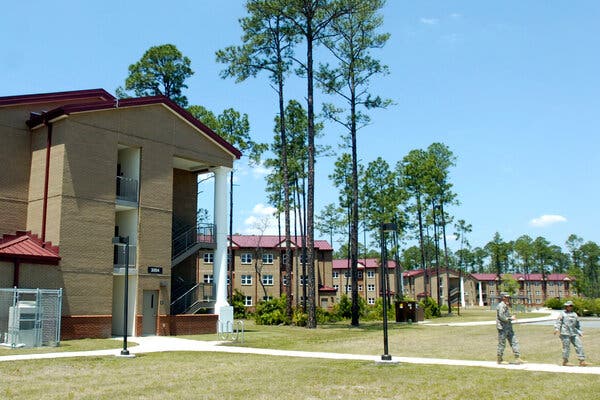 Multistory beige buildings with red trim and roofs that make up the barracks at Fort Stewart in Georgia.