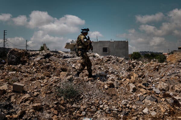 A soldier walking through a field of debris.