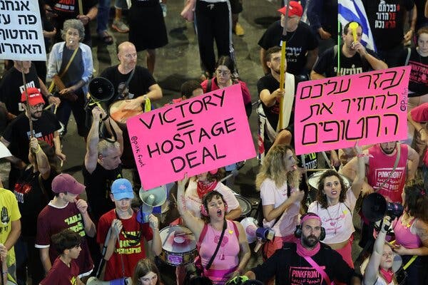 Demonstrators gather. One holds a sign stating, “Victory = hostage deal.”