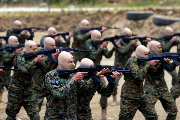 Men with head masks aim rifles in a training exercise. 