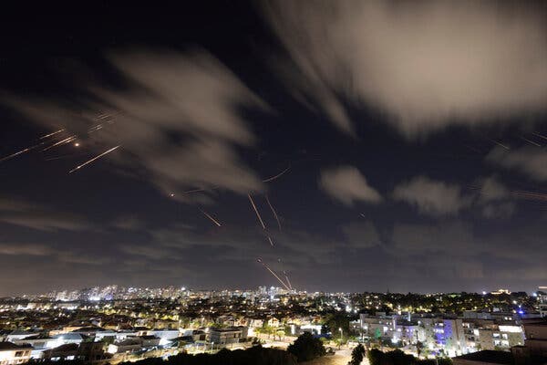 Streaks of light in the night sky over an urban area.